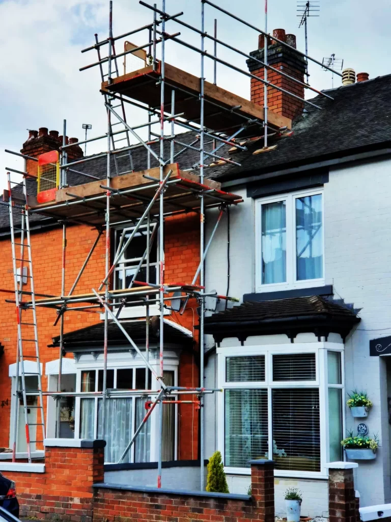 Scaffolding on a brick and white rendered house