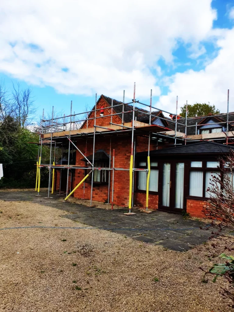 Scaffolding on a red brick house seen from the block-paved driveway