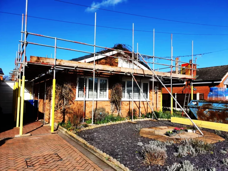 Scaffolding across the front of a bungalow under a blue sky