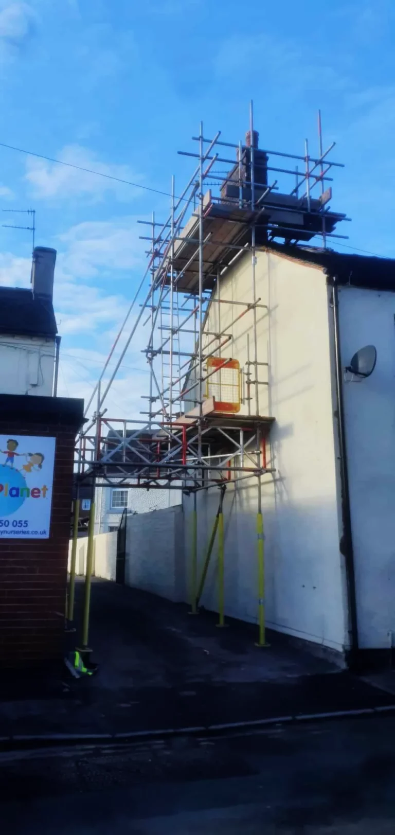 Tall scaffold up a chimney stack on a white house