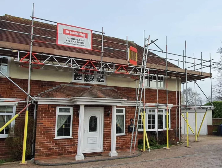 Scaffolding with an EB Scaffolding sign on a red brick house