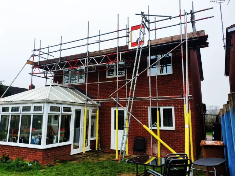 Scaffolding on a brick house with a conservatory