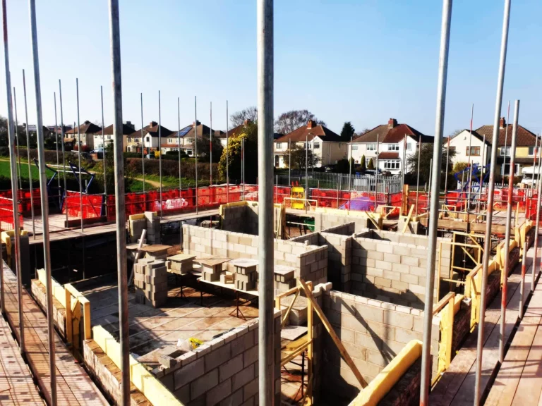 Scaffolding around new-build foundations with houses behind