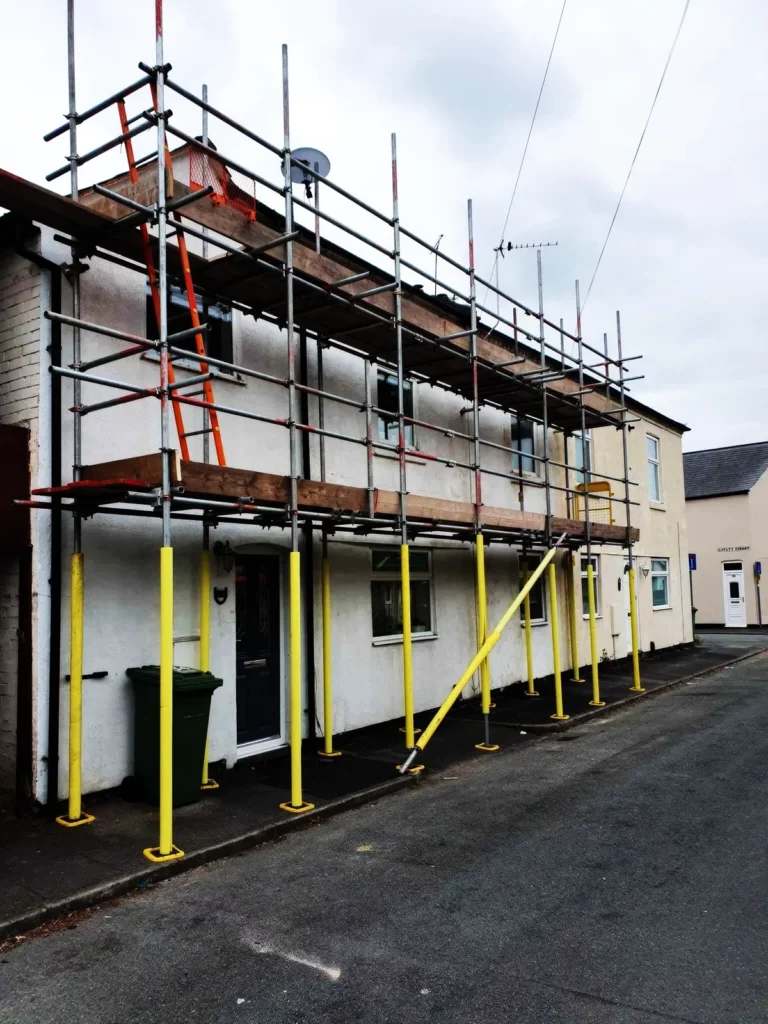 Scaffolding along the front of a white terraced house on a street